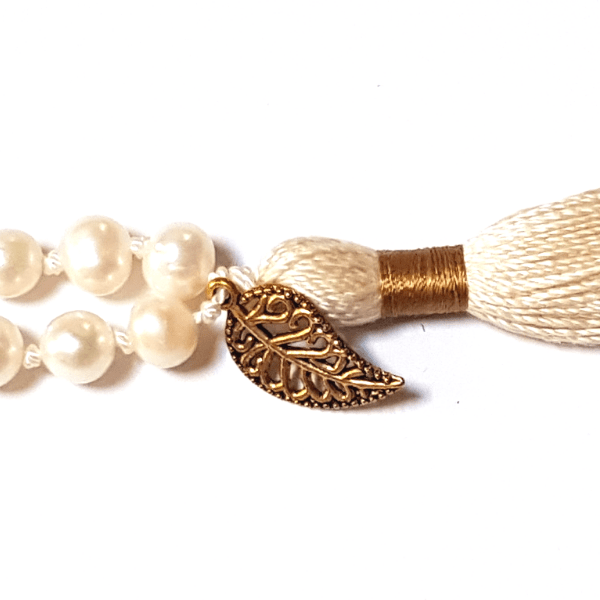 Close up of handmade Wisdom Mala – Freshwater Pearls, Quartz & Rudraksha Bead necklace gold leaf charm on tassel 