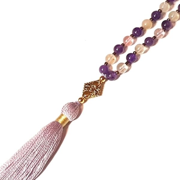Close up of handmade Amethyst, Quartz and Rudraksha mala necklace with gold coloured metal guru bead
