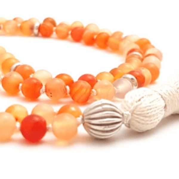 Close up of Handmade Carnelian Sacral Chakra Mala necklace curled on table