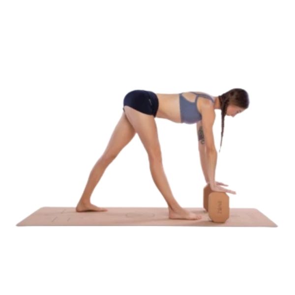 Woman standing with legs apart in v shape on cork yoga mat and leaning forward using two cork Zone yoga rectangular blocks with corners cut at an angle to balance hands on and support pose