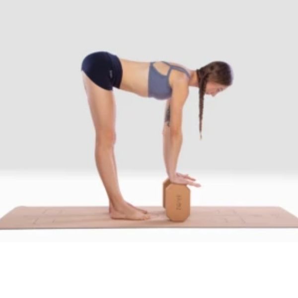 Woman standing on cork yoga mat and leaning forward using two cork Zone yoga rectangular blocks with corners cut at an angle to balance hands on and support pose