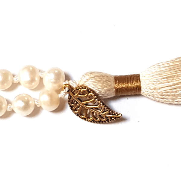 Close up of handmade Pearl, Quartz and Rudraksha Mala necklace leaf charm on tassel 