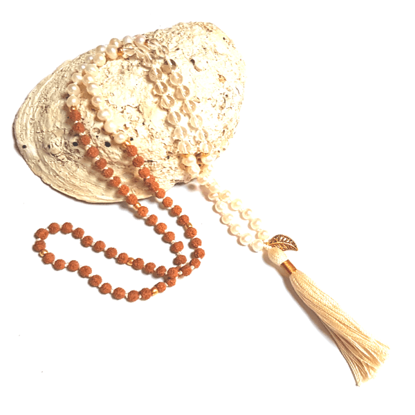 Handmade Pearl, Quartz and Rudraksha Mala necklace with leaf charm on tassel  drapped over back of an ablone shell