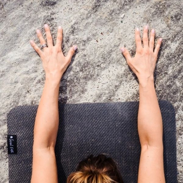 Woman's head and arms laid on edge of black second earth yoga mat